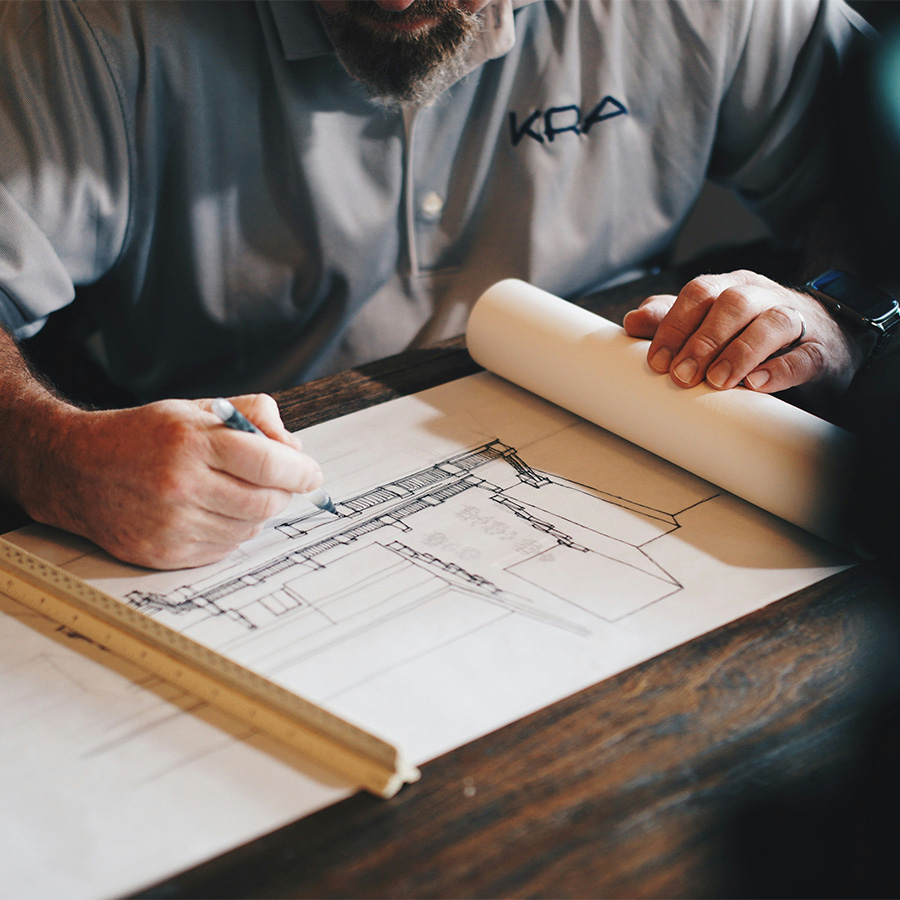 Architect working with pen and ruler on building drawing.