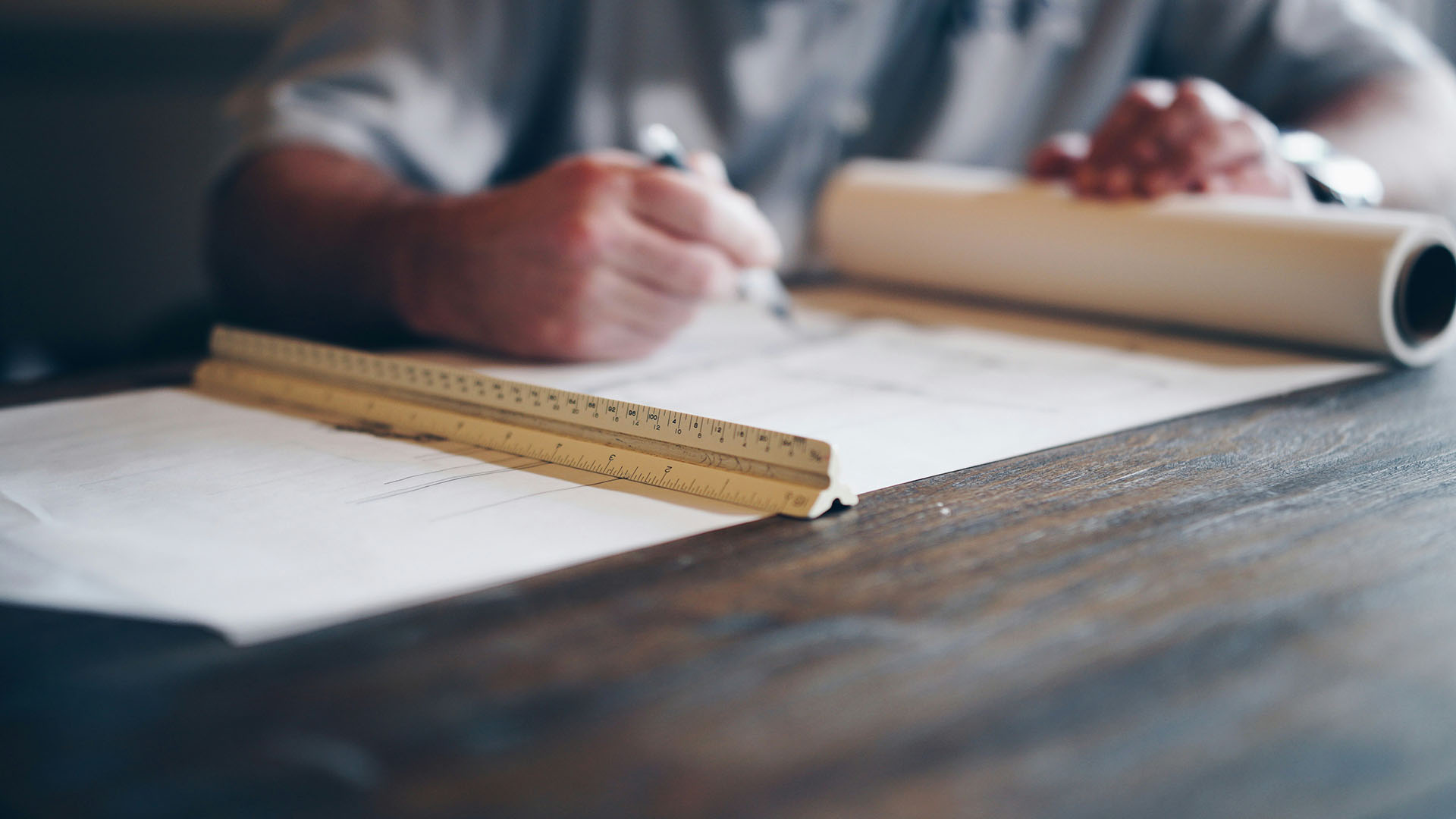 Architect working on plans with pen and ruler.