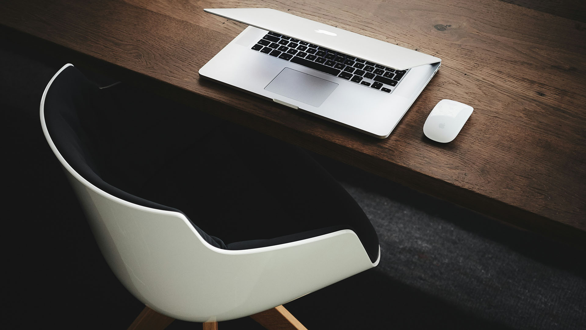 Elegant wood desk and chair with laptop computer and mouse.