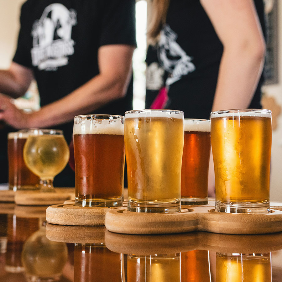 Flights of beers on wood bar top at brewery.