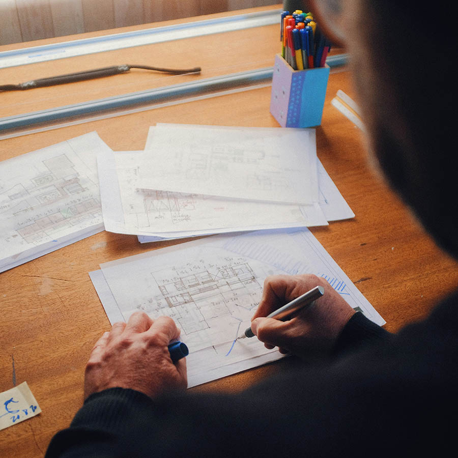 Architect working with pen and paper on building drawing.